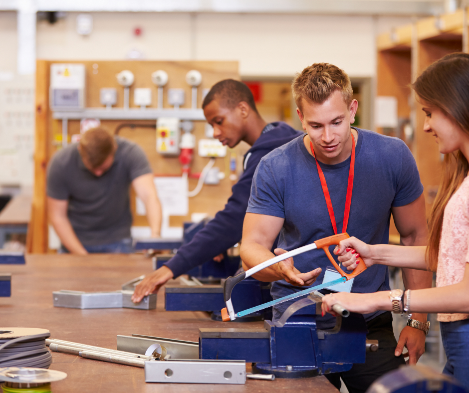 Atelier de formation professionnelle avec formateur et stagiaires pratiquant sur équipement technique.